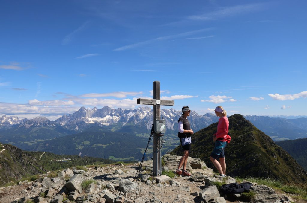Ein Kreuz mit zwei Personen daneben in den Bergen von Ramsau