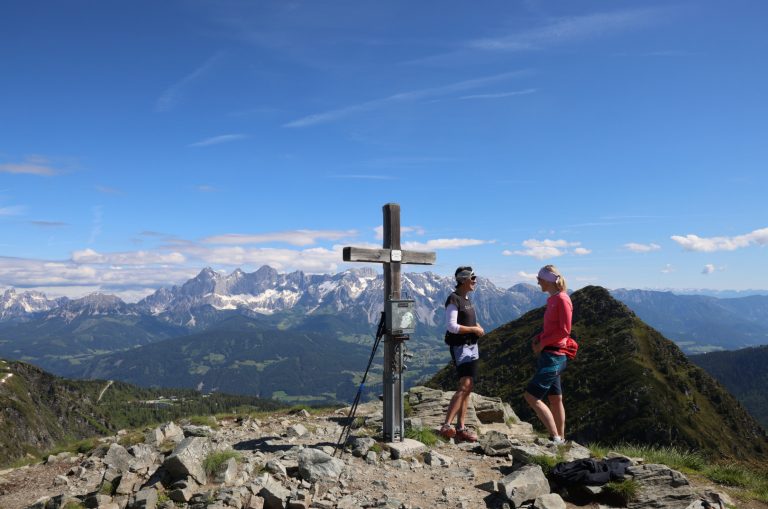Ein Kreuz mit zwei Personen daneben in den Bergen von Ramsau