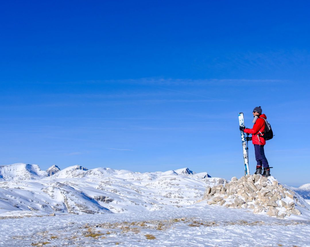 ein Skitouren-Geher auf dem Plateau des Gipfels Großes Tragl. Im Hintergrund Gipfel im Toten Gebirge wie beispielsweise Großer Priel im linken Bilddrittel, Blick in Richtung Nordosten.