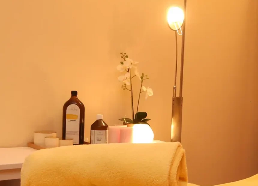 Die Massagebank ist in einem gemütlichen Licht mit aufgerollten Handtüchern und Massageölen im Hintergrund zu sehen.