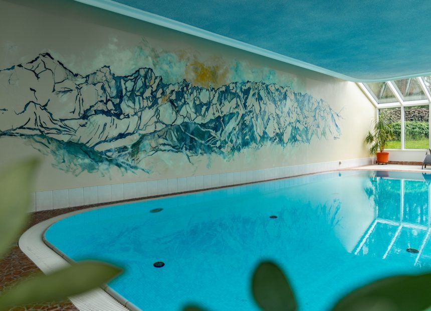 Großzügiges Hotel-Hallenbad mit Wandmalerei, die Berge zeigt.
